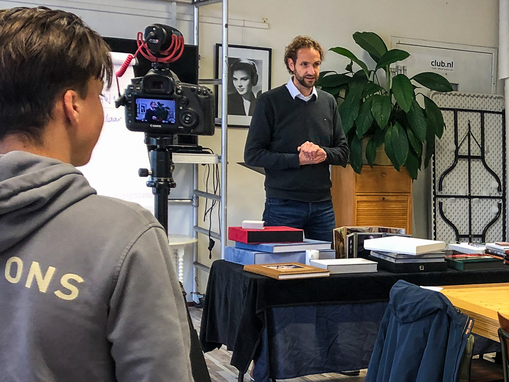 Marcel Heekelaar voor een tafel vol fotoalbums en andere materialen van nPhoto en Eprint tijdens een lesdag bij de opleiding Bekwaam Afscheidsfotograaf